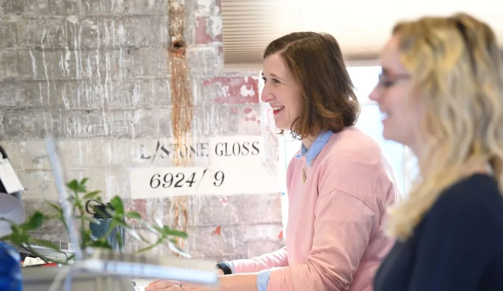 Two women reviewing work on a screen in an office
